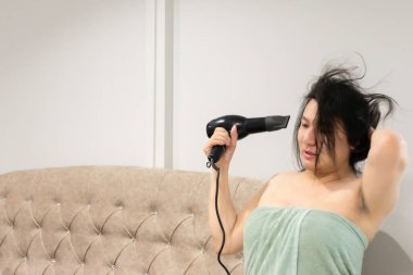 Taylandlı LGBTQ çalışanı duş aldıktan sonra saçlarını kurutuyor. Yatakta dinleniyor. Gece rutinine hazırlanıyor.