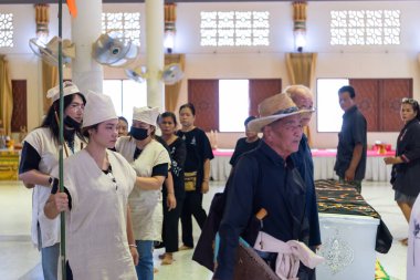 Suphanburi, Tayland - 7 Kasım 2025 Tay Song Barajı cenaze alayı, basit giysiler içinde, tütsü ve portreler taşıyan, ölüm rehberliği ayininde ruhani bir liderin rehberliğinde.