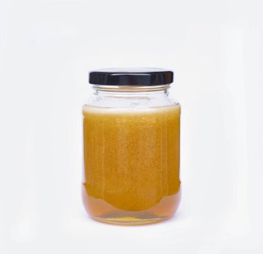 Siyah kapaklı kavanozdaki izole edilmiş sarı bal, doğanın beyaz arka planında kesme yolu ile tatlı ya da tatlı bir yemektir..