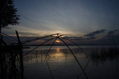 Kare dalış ağının gölgeleriyle gelen sıcak ışık Tayland 'ın güneyindeki Songkhla Gölü çevresindeki insanların halk yolunu yansıtıyor..