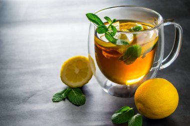 Şeffaf bir fincanda limonlu ve naneli çay. Tedavi için alternatif tıp.