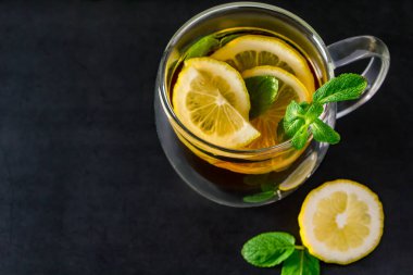 Koyu arkaplanda limonlu ve naneli bitki çayı. Rahatlamak ve ferahlamak için lezzetli bir içecek.