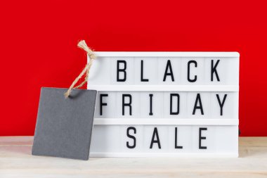 Kara Cuma indirim konsepti. Kırmızı arkaplanda etiket ve ışık kutusu. Reklam afişi.