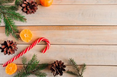 Yeni yıl dekoru. Noel ağacı dalları, çam kozalakları, mandalina ve şekerler ahşap bir arka planda.