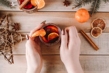 Kadın elinde bir bardak sıcak sıcak şarap tutuyor. Tatiller için ılık kış içeceği.