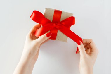 Beyaz arka planda kırmızı kurdeleli bir hediye. 