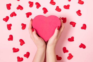 Kadın elleri büyük pembe bir kalp tutuyor. Sevgililer Günü konsepti, metin yeri