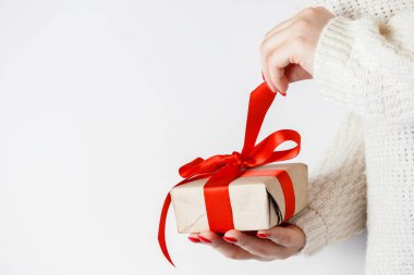 El işi kağıdında kırmızı kurdeleli genç bir kadın. Sevgililer Günü için hediye paketini açıyorum..