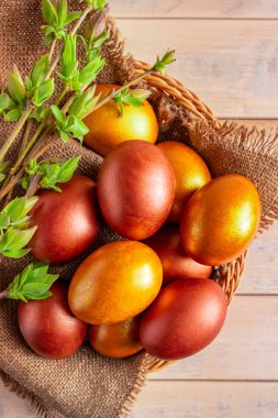 Tahta bir arka planda hasır sepette altın Paskalya yumurtaları. Bahar sembolü Dikey fotoğraf.