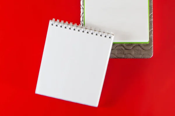 Minimalistic layout for design. Office supplies - notebooks and pens on a red background. Open blank notebook for your notes on a red background