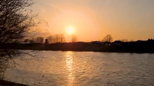 Закат над рекой. Быстрый поток воды. Яркие лучи солнца отражаются в воде. Природный пейзаж Силуэт деревьев на горизонте. — стоковое видео