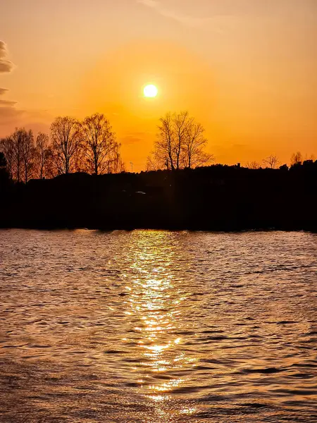 Захід сонця над річкою. Сонце відбивається у воді. Шлях сонячного світла. — стокове фото