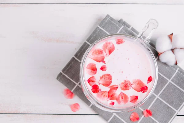 月球牛奶 粉红相扑与玫瑰花瓣 透明的杯与时髦的纯素食主义者在白色背景下搅拌茶 睡觉时放松饮料 — 图库照片