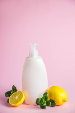 Limon yağlı organik kozmetik ürünler. Pembe arka planda narenciyeli bir şişe nemlendirici. Metin için yer.