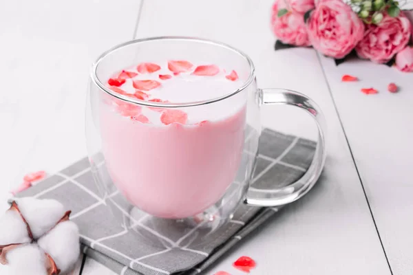 月球牛奶 粉红相扑与玫瑰花瓣 透明的杯与时髦的纯素食主义者在白色背景下搅拌茶 睡觉时放松饮料 — 图库照片