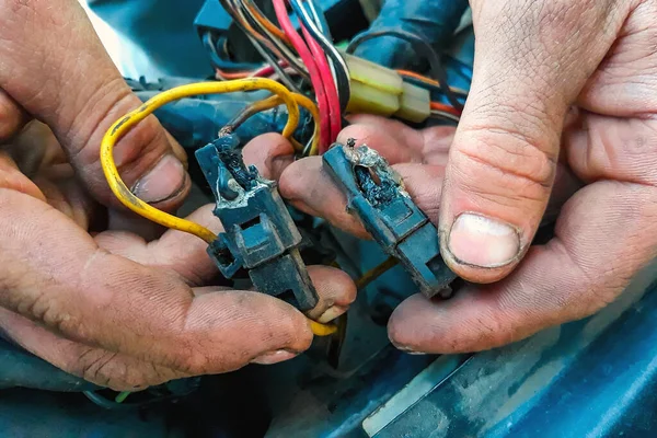 stock image Short circuit in the car. Male electrician holding a charred wires. Vehicle repair, car service station