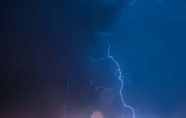 Gece gökyüzünde şimşek çakıyor. Şehir üzerinde fırtına var. Fırtınalı kara bulutlar ve yağmurlu hava.