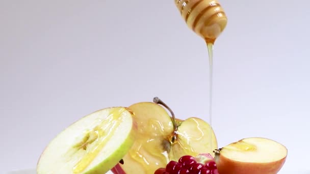 Солодкий мед капає на яблука і гранати на білому тлі. Щаслива Рош Хашана. Символи єврейського свята Новий рік. — стокове відео