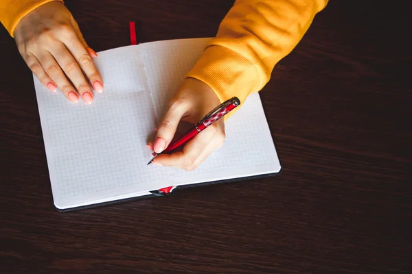 Kobieta pisze w notatniku i trzyma długopis lewą ręką. Dziewczyna pracuje w biurze. Dzień Leworęcznych 13 sierpnia. — Zdjęcie stockowe