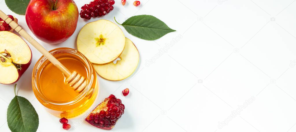 Happy Rosh Hashanah. Traditional Jewish holiday New Year. Apples, pomegranates and honey on a white background. Banner format, place for text.
