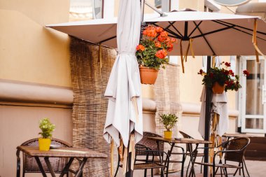 Eski kasabadaki sokak kafesi. Boş masalar ve sandalyeler. Sonbahar şehri manzarası. Eski tarz, modaya uygun nötr renkler.