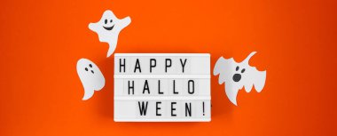 Mutlu Cadılar Bayramı. Turuncu arka planda tatil için komik kağıt hayaletler. Sancak biçimi.