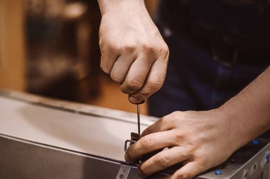 Mobilya montajcısı tornavidayla çalışır. Erkek işçi metal mandal takıyor. Eller tamir aletini tutsun. Küçük işletme desteği. İnşaat atölyesinde yaşam tarzı.