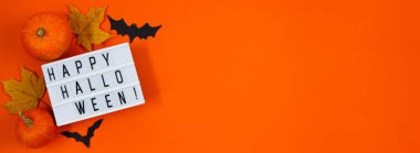 Mutlu Cadılar Bayramı. Turuncu arka planda balkabakları ve sonbahar yaprakları. Metin için yer, pankart biçimi