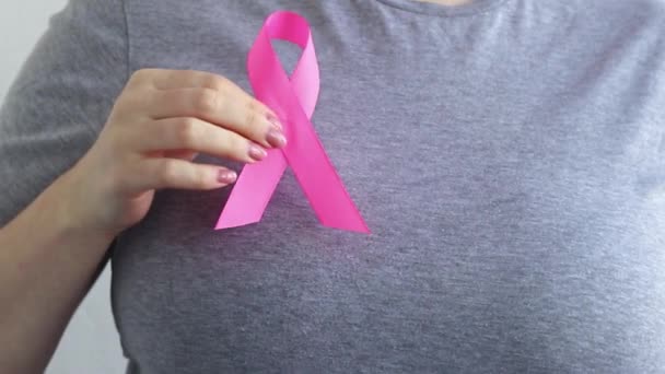 乳がん啓発月間 女性はピンクのリボンを手に持っている サポートとヘルプの概念 癌との闘いの象徴 — ストック動画
