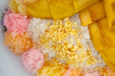 Yapışkan pirinç ve susam üstünde belgili tanımlık tepe ile mango