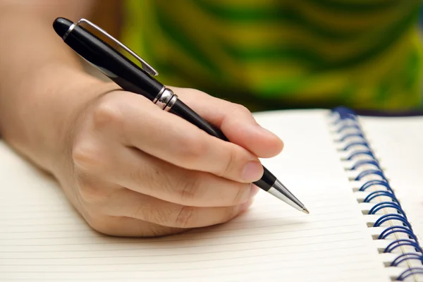 Mano tenere una penna e scrivere su un libro — Foto Stock