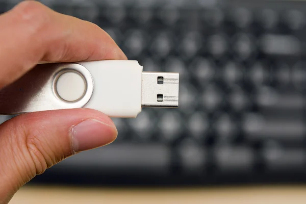 Ręka trzymać puste Usb kciuk przejażdżka z klawiatury w tle — Zdjęcie stockowe