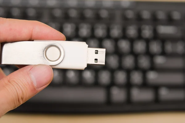 Ręka trzymać puste Usb kciuk przejażdżka z klawiatury w tle — Zdjęcie stockowe