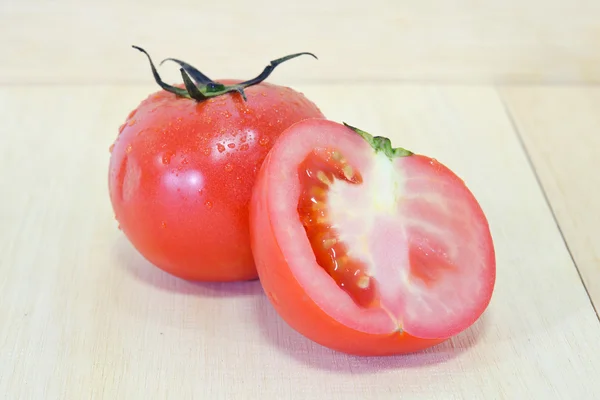 Tomatenfrüchte mit halbem Querschnitt isoliert auf hölzernem Hintergrund — Stockfoto