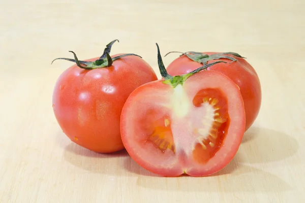Tomatenfrüchte mit halbem Querschnitt isoliert auf hölzernem Hintergrund — Stockfoto