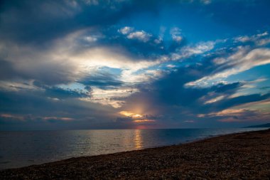 Deniz kıyısında şafak sökerken, deniz kabuğu kayaları ile kaplı