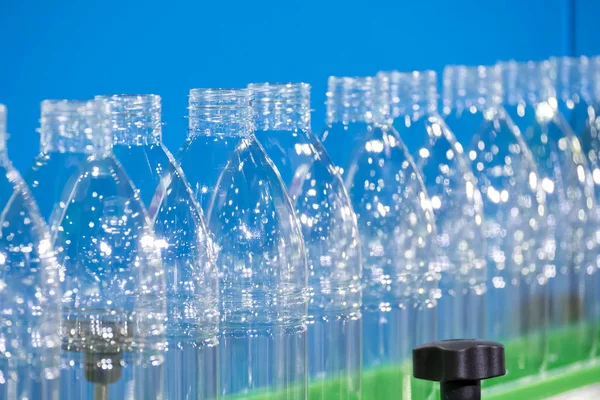 The PET bottles  on the conveyor belt for filling process in the drinking water factory. The hi-technology of plastic bottle manufacturing process.