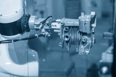 The robotics arm gripping the motorcycle engine parts. The hi-technology  autonomous manufacturing process of automotive parts. clipart