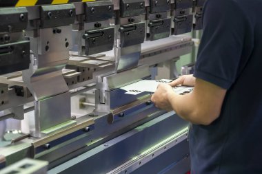 Teknisyenle hidrolik bükme makinesi operasyonu. Teknisyen ile fren bükme makinesinin yaptığı levha metal üretim işlemi..