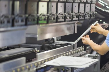 Teknisyenle hidrolik bükme makinesi operasyonu. Teknisyen ile fren bükme makinesinin yaptığı levha metal üretim işlemi..