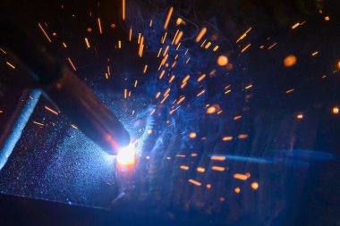 Elektrik kaynaklama işleminin yakın çekim sahnesi. İnşaat alanındaki kaynak operasyonu.. 