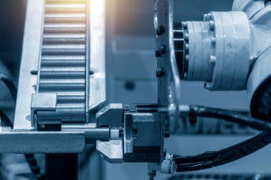 Robotik sistem tarafından yüksek teknolojili materyal işleme süreci. Üretim hattındaki metal şaft parçalarını tutan otomatik robot kol.. 