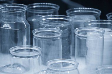 Açık mavi sahnede şeffaf plastik konteynır grubu. Yüksek teknoloji konteynır ürünleri üretim süreci kavramı.