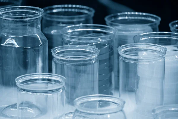 Açık mavi sahnede şeffaf plastik konteynır grubu. Yüksek teknoloji konteynır ürünleri üretim süreci kavramı.