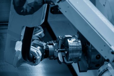 CNC torna makinesinin metal parçalarını tutan otomatik robot kolu. Dönüşüm makinesinde robotik sistem tarafından yüksek teknoloji materyal işleme süreci. 