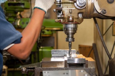 Makine operatörü metal plaka üzerindeki deliği NC değirmen makinesiyle deliyor. NC değirmen makinesinin atölye çalışması.