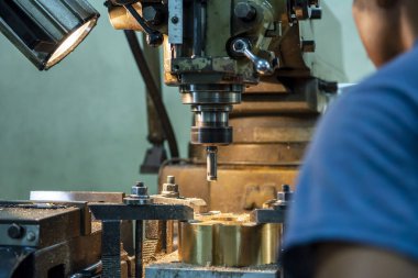 Makine operatörü metal plaka üzerindeki deliği NC değirmen makinesiyle deliyor. NC değirmen makinesinin atölye çalışması.