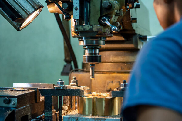 The machine operator drilling the hole on metal plate with NC milling machine. The shop floor operation by NC milling machine.