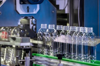 İçme suyu fabrikasındaki işlemleri tamamlamak için konveyör bandındaki boş PET şişeleri. Plastik şişe üretim sürecinin yüksek teknolojisi..