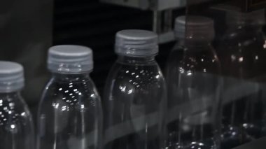 Yavaş çekim sahnesi taşıyıcı bantta içme suyu şişeleriyle dolu. İçme suyu üretim sürecinin yüksek teknolojisi. 